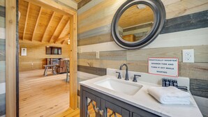 A bathroom with a wooden interior, a sink with a mirror, and a sign indicating to turn off the shower while soaping. - Pet-friendly Hideaway 13 Mi to Leakey (Leakey)