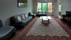 A living room with a sofa set, a coffee table, a ceiling fan, and a large window with curtains.