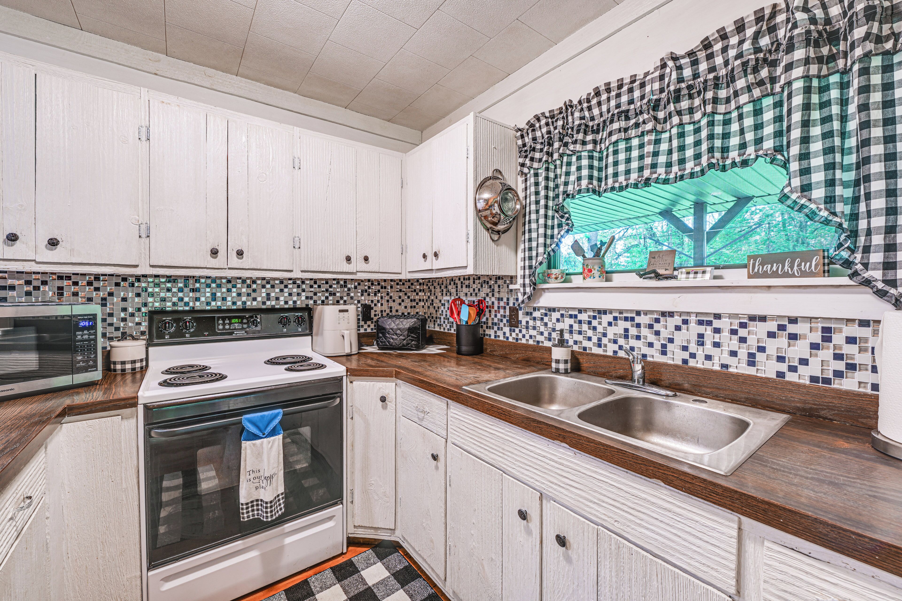 A kitchen with white cabinets, a microwave, a stove, and a sink.