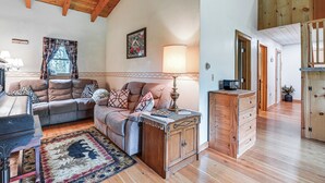 A cozy living room with a sofa, a wooden cabinet, and a lamp. - Near State Parks: Countryside Cottage in Wellsboro (Wellsboro)