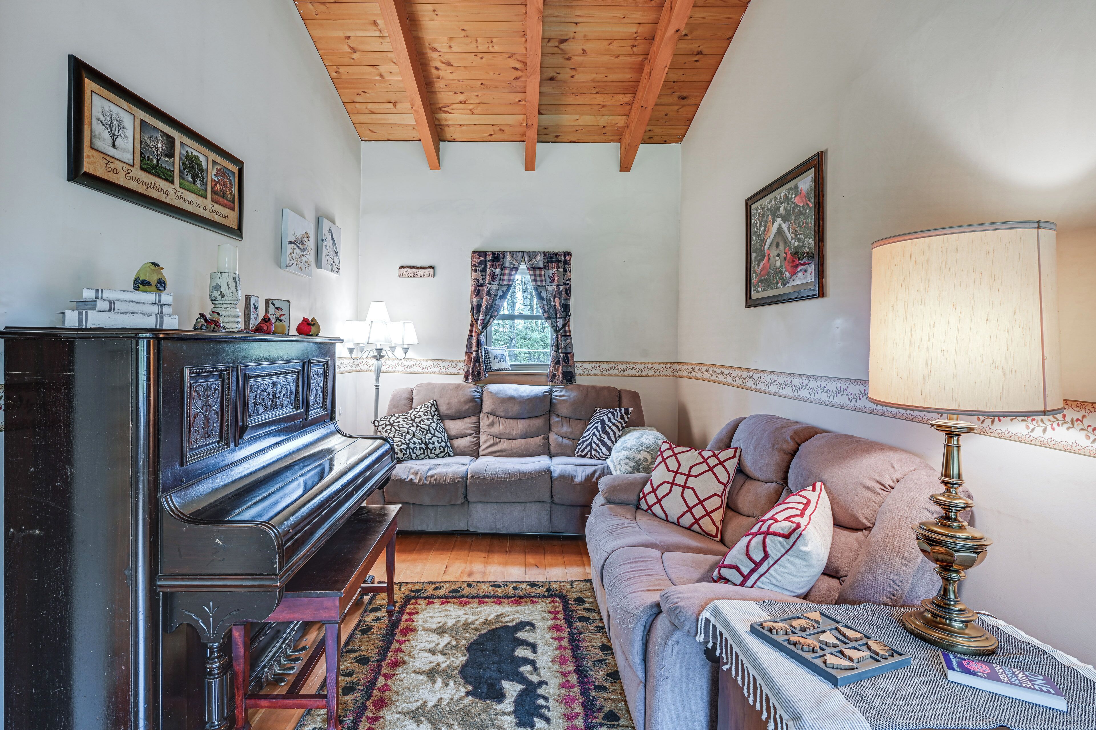 A cozy living room with a piano, a sofa, a lamp, and a rug.