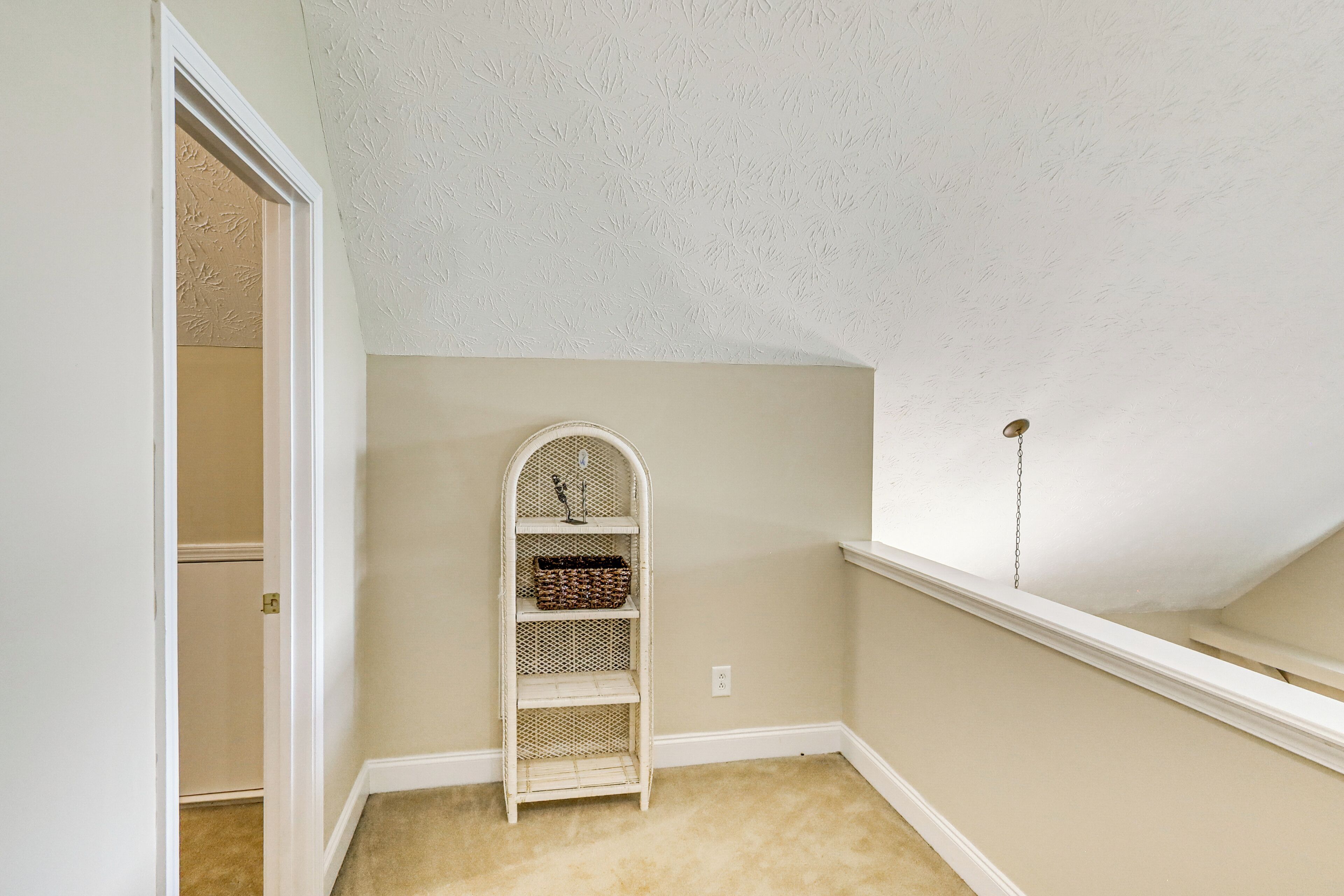 Un rincón de una habitación con techo blanco, pared blanca y alfombra color beige.