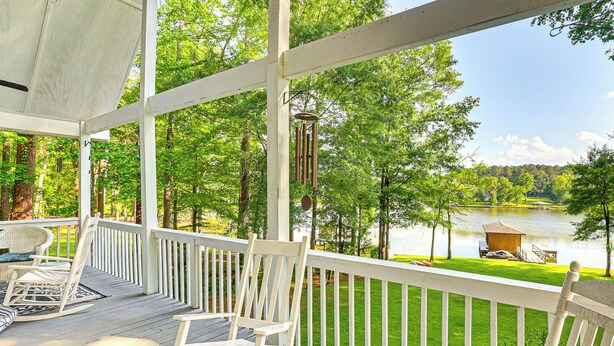 A wooden deck with white railings, overlooking a lake and trees. - Secluded 6BR Sinclair Lake House w/ Dock (Eatonton)