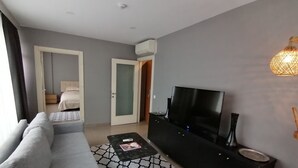 A modern living room with a grey sofa, a black entertainment unit, and a flat-screen TV. - Non-Smoked Apartments at Levent (İstanbul)