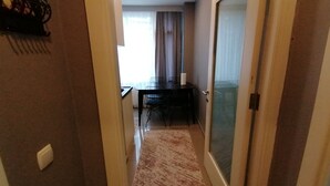 A narrow hallway with a carpeted floor leading to a dining area with a table and chairs. - Non-Smoked Apartments at Levent (İstanbul)