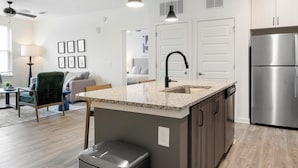A modern kitchen with granite countertops, a stainless steel refrigerator, and a built-in dishwasher.