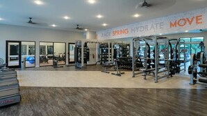 A spacious gym with cardio machines, weightlifting equipment, and a mirrored wall.