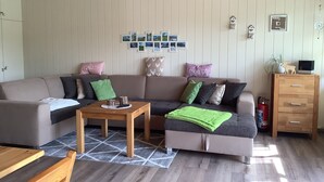 Ein modernes Wohnzimmer mit einer Eckcouch, einem Holztisch und einem Kamin.