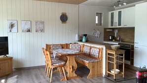 Eine gemütliche Küche mit Holzmöbeln, einem Esstisch mit Stühlen und einer fest eingebauten Bank.
