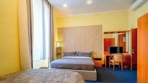 Quarto de hotel com uma cama grande, uma escrivaninha, uma cadeira e uma televisão.