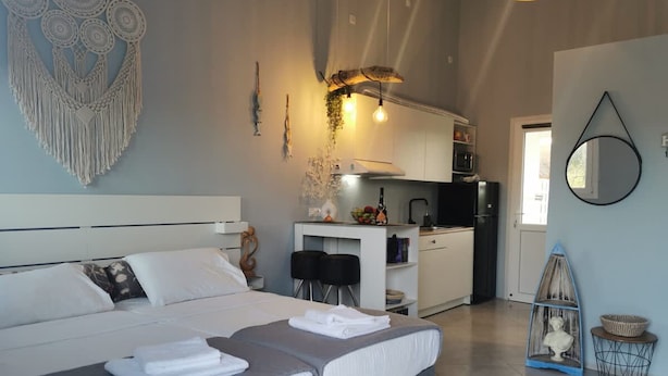 Een moderne slaapkamer met een groot bed, een kleine kitchenette en een eethoek.