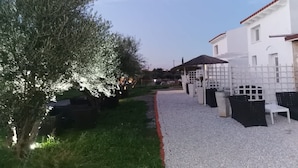 Een grindpad dat leidt naar een wit gebouw met een overdekte terras.