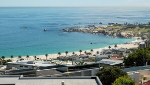 A coastal view with a beach, ocean, and buildings. - Ocean View 2 bed Apt in Camps Bay Skyline Heights (Cape Town)