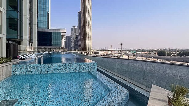 A rooftop pool with a view of a city skyline and a body of water. - The Art of Living Missoni Inspired Luxury Studio (Dubai)