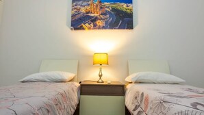 A hotel room with two beds, a nightstand with a lamp, and a wall-mounted painting of a cityscape. - Front Sea View Three bdr Apartment 200 sqm (Tas-Sliema)