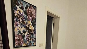 A room with a round table and two chairs, a large abstract painting on the wall, an air conditioning unit, and a door. - Front Sea View Three bdr Apartment 200 sqm (Tas-Sliema)