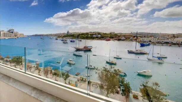 A marina with boats, a clear sky, and a distant cityscape. - Front Sea View Three bdr Apartment 200 sqm (Tas-Sliema)