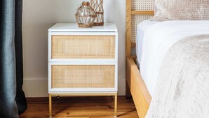 A bedroom with a wooden bed, white bedside tables, a wall-mounted lamp, and a woven basket with dried flowers. - The 1300 | 2 Designer Homes, Walk to St Charles (New Orleans)
