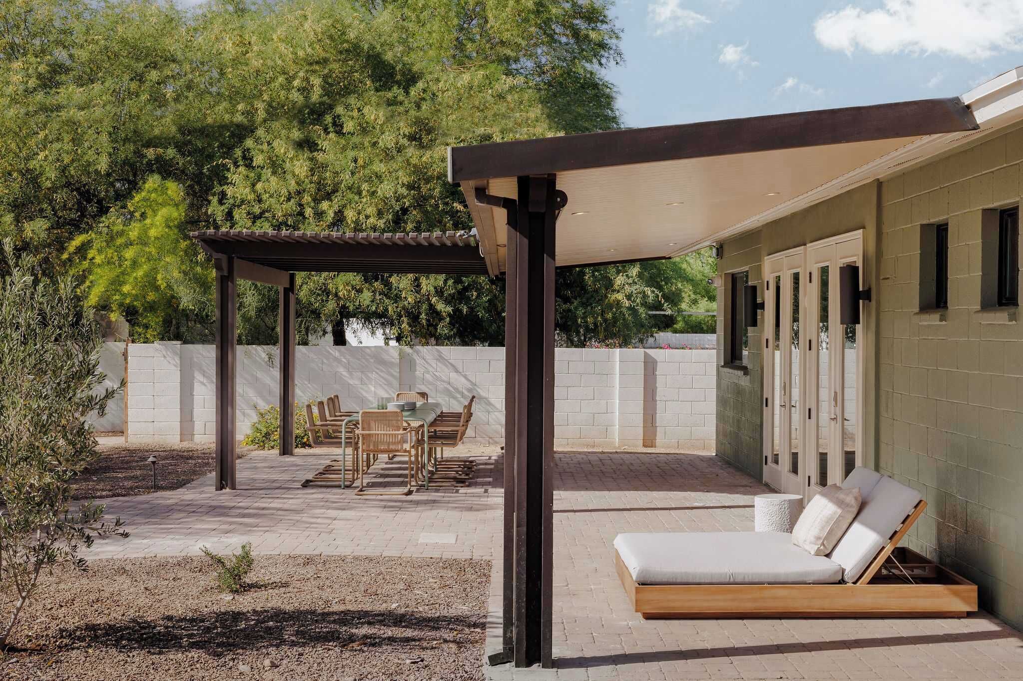 Eine Außenpatio mit einer Pergola, einer Liege und einem Essbereich mit Stühlen und einem Tisch.
