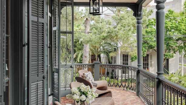 A covered porch with wicker furniture, a hanging lantern, and a tiled floor. - The Estella | 12-bedroom Suite, Shared Pool (New Orleans)
