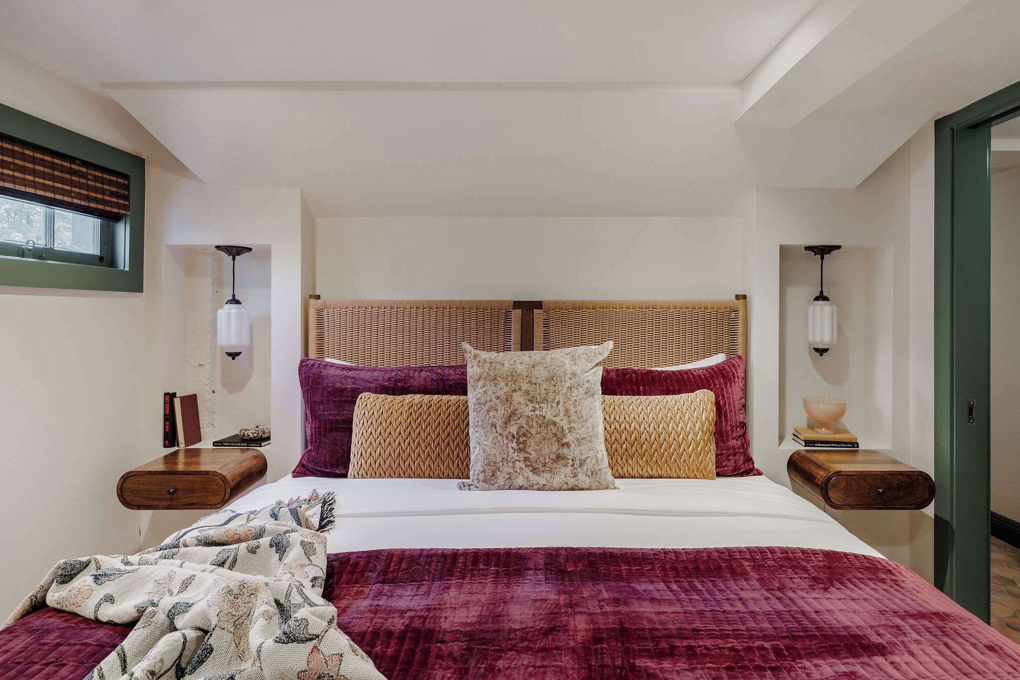 A neatly arranged bedroom with a large bed, two bedside tables, and a window with blinds.