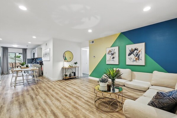Relax in this stylish living space with a comfortable sofa, dining area, and large accent wall.