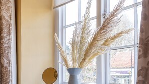 A window with a vase of pampas grass on a windowsill.