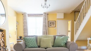 A living room with a sofa, ottoman, and a chandelier.