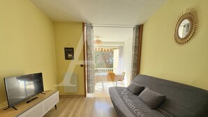 A living room with a sofa, TV, and a small table. - T2 SPACIEUX, LOGGIA ET ACCES WIFI (Sète)