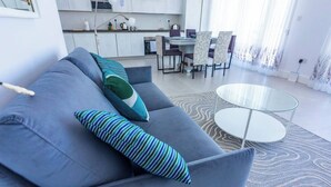 A modern living room with a grey sofa, striped pillows, a glass coffee table, and a patterned rug. - Valletta Penthouse Cathedral view Terrace (Valletta)