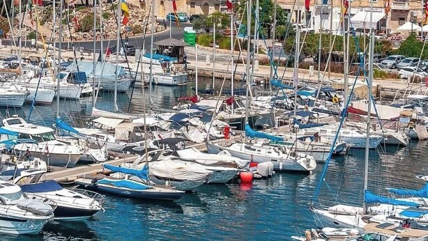 A marina with numerous boats docked, a historic building with a red dome, and multiple flags flying. - Valletta Penthouse Cathedral view Terrace (Valletta)