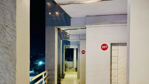 A corridor with a view of a bridge at night, leading to rooms numbered 207 and 208. - Hotel Sai Navsari (Jalalpore)