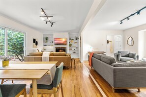 A spacious living area with a wooden dining table, a gray sofa, and a fireplace. - Spacious 4-bedroom house with Fenced-In backyard near UNC and Chapel Hill (Carrboro)