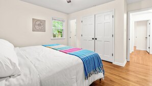 Een slaapkamer met een bed, een plafondventilator, een raam en een deur.