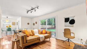 Een moderne woonkamer met een leren bank, een eettafel en een groot raam met uitzicht op de omgeving.