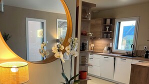 Una cucina moderna con un grande specchio rotondo, un tavolino consolle in legno con una lampada e un'orchidea in vaso.