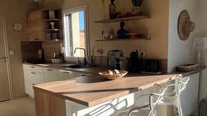 Una cucina moderna con un'isola in legno, sgabelli da bar bianchi e un'ampia finestra.