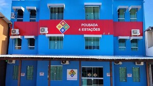 A building with a blue facade and a red sign that reads "POUSADA 4 ESTAÇÕES". - Pousada 4 Estações (Penha)