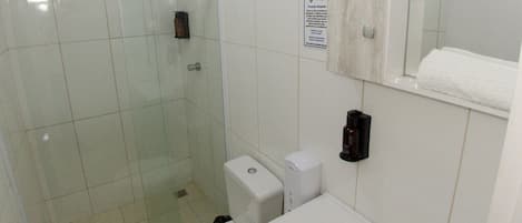 Un baño moderno con cabina de ducha de vidrio, inodoro, lavabo y espejo.