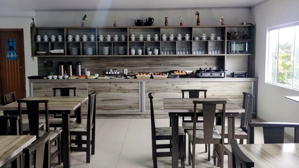A modern kitchen with wooden cabinets, a central island, and a dining area with wooden tables and chairs. - Pousada 4 Estações (Penha)