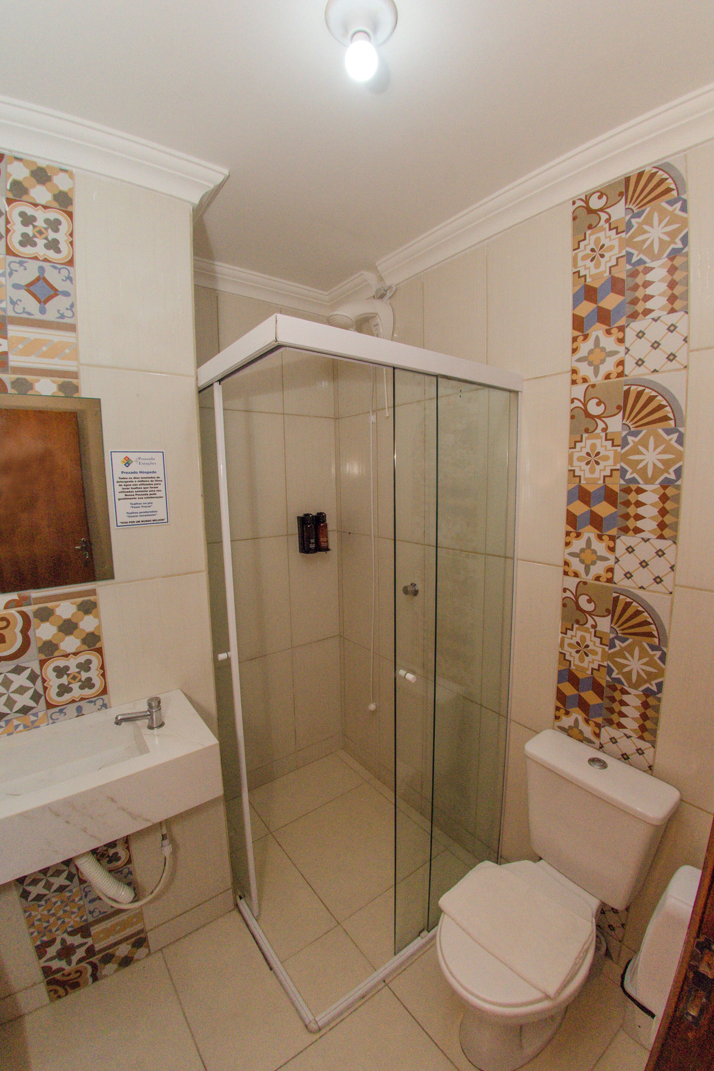 A bathroom with a glass-enclosed shower, a toilet, and a sink.