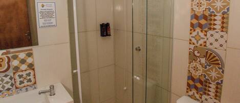 A bathroom with a glass-enclosed shower, a toilet, and a sink.