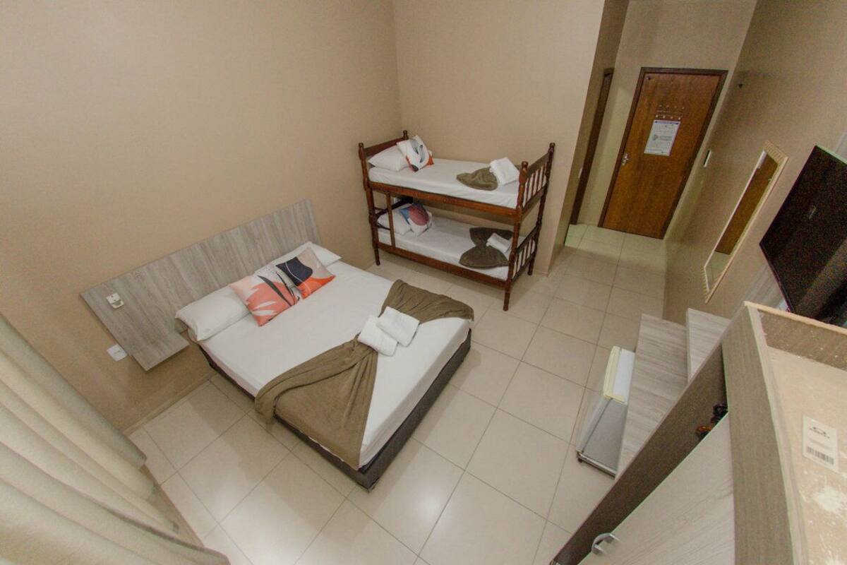 Ein Hotelzimmer mit einem Einzelbett, einem Etagenbett und einer Tür.