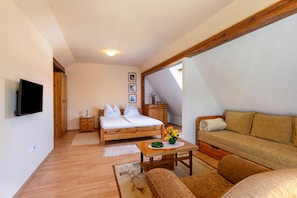 A room with a bed, a sofa, a TV, wooden furniture, and a small table with a vase. - Lakeside Serenity House (Balatonbereny)