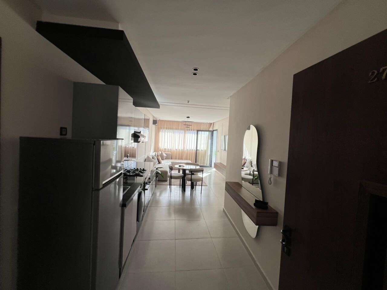 A modern kitchen with a refrigerator, stove, and dining area with a table and chairs.