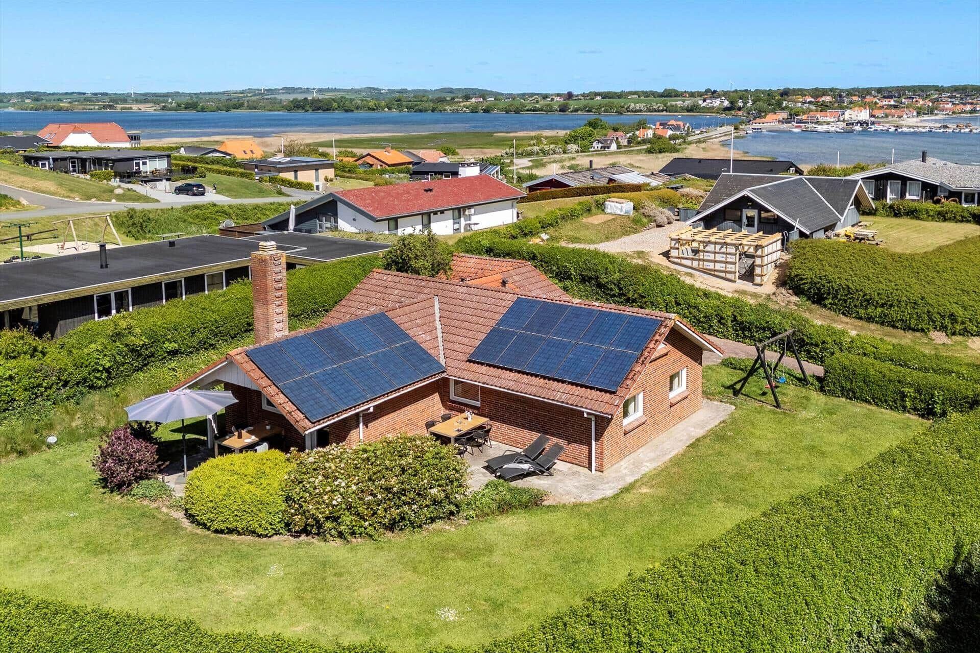 A residential property with solar panels, a swimming pool, and a view of a lake and town.