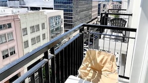 A balcony with a small table and chairs, a view of the cityscape, and a grassy area. - Room-the B's Crib Saint Dominique (Iloilo)