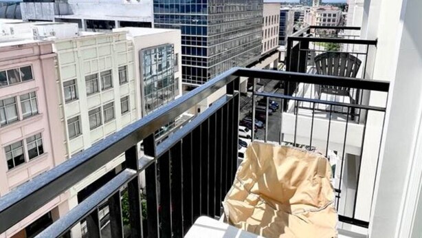 A balcony with a small table and chairs, a view of the cityscape, and a grassy area. - Room-the B's Crib Saint Dominique (Iloilo)