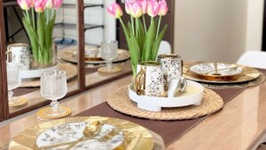 A dining table with a reflective surface, a vase of pink tulips, and a tray with a teapot and cups. - Room-the B's Crib Saint Dominique (Iloilo)