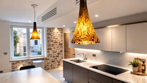 A modern kitchen with a marble countertop, two pendant lights, a built-in sink, and a stone wall. - Very large, refined apartment in the heart of old Antibes (Antibes)